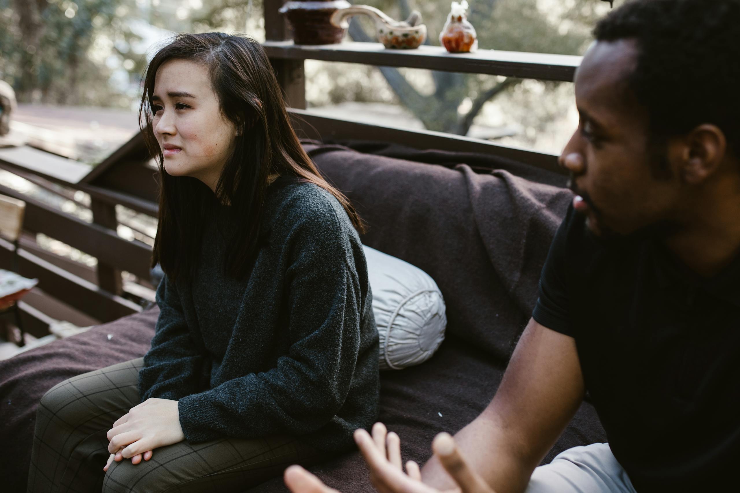 A man and woman having an emotional discussion on an outdoor bench.