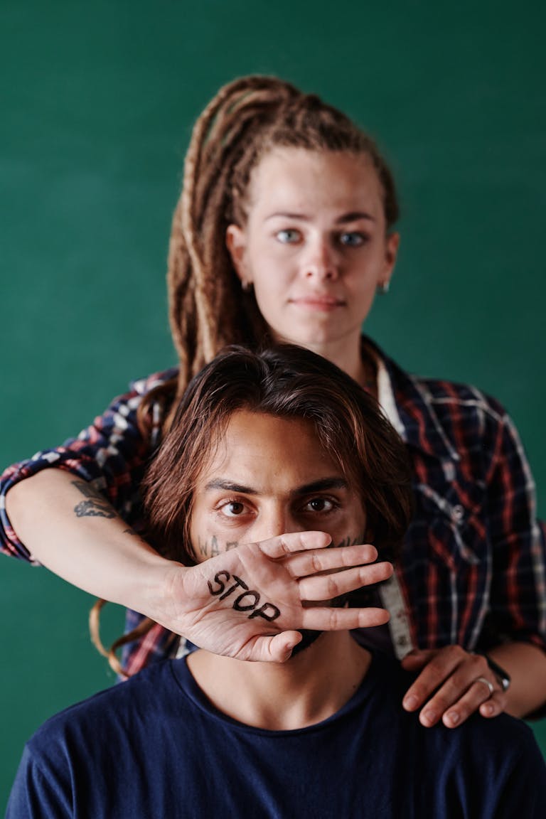 Two people highlighting social issues with 'stop' message on hand in a studio shot.