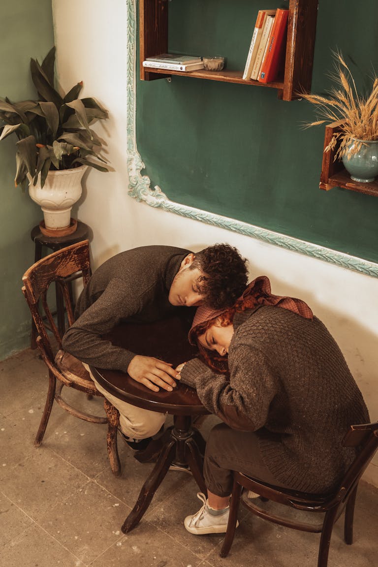 A cozy couple asleep at a café table, reflecting warmth and intimacy in a vintage setting.