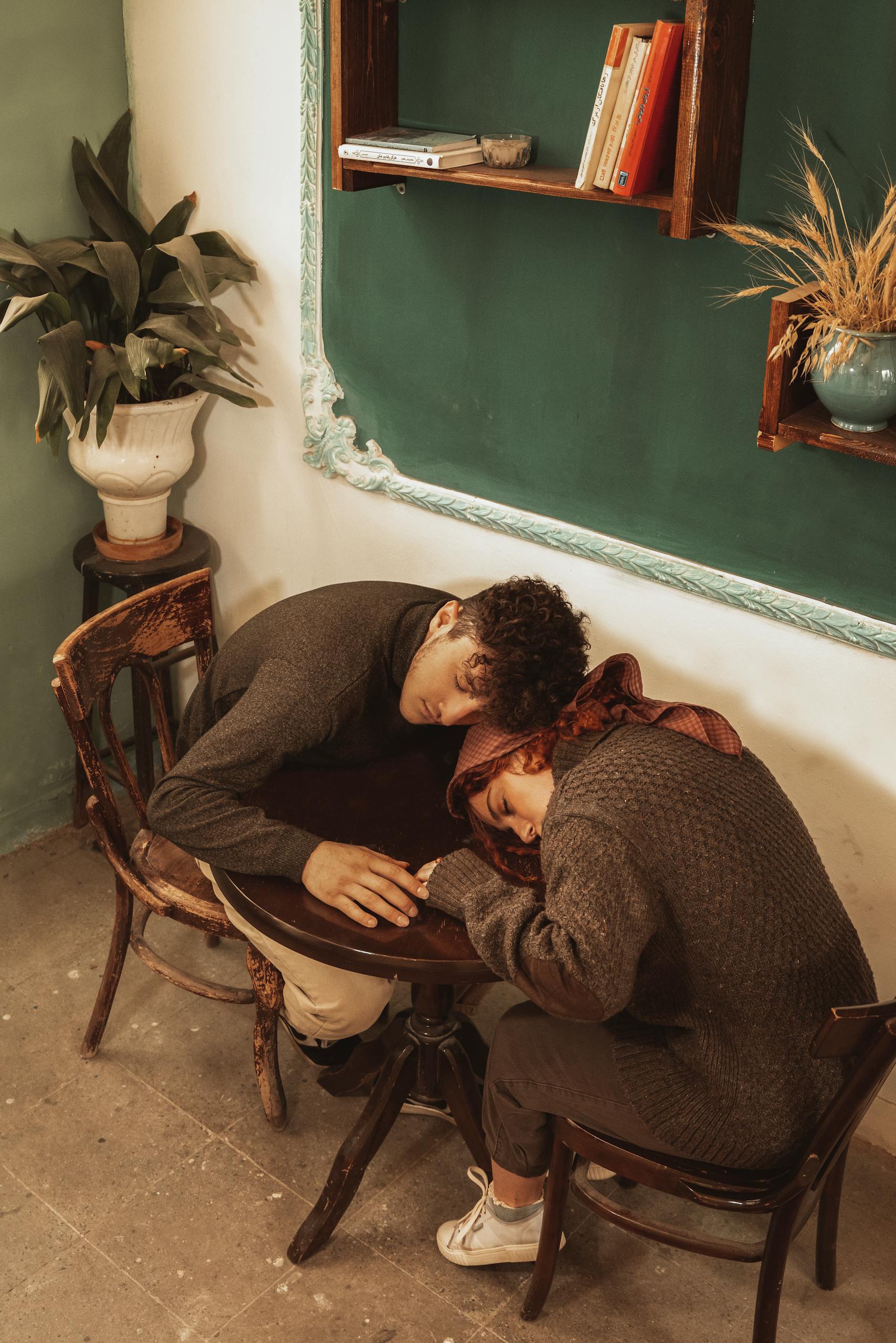 A cozy couple asleep at a café table, reflecting warmth and intimacy in a vintage setting.