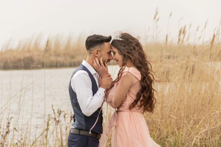 A romantic couple sharing an intimate moment outdoors by the water.