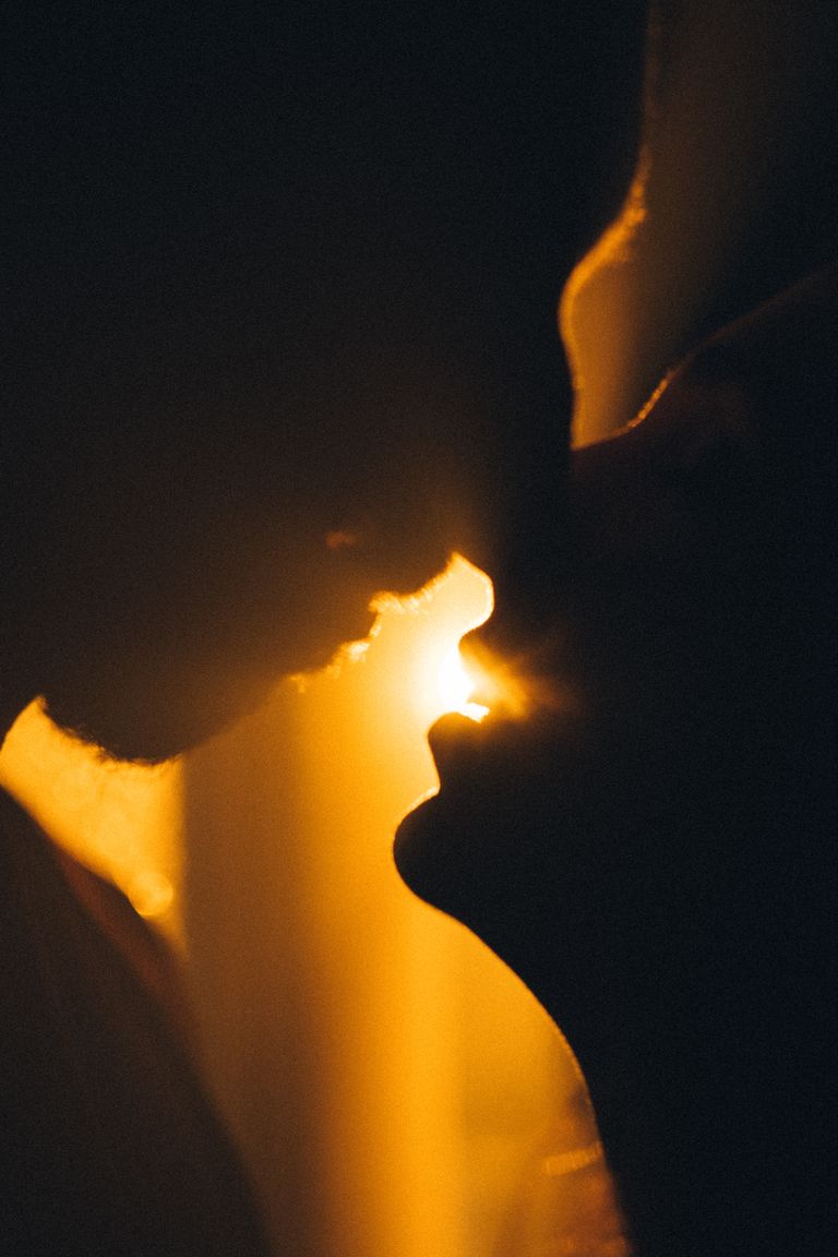 A close-up of a couple kissing, captured in a warm, dramatic silhouette during sunset in Baku, Azerbaijan.